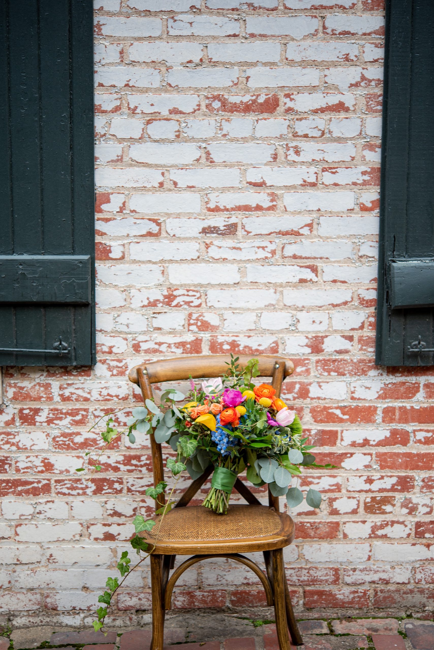 bride's bouquet sits on wooden chair against brick wall in Old Town Alexandria 