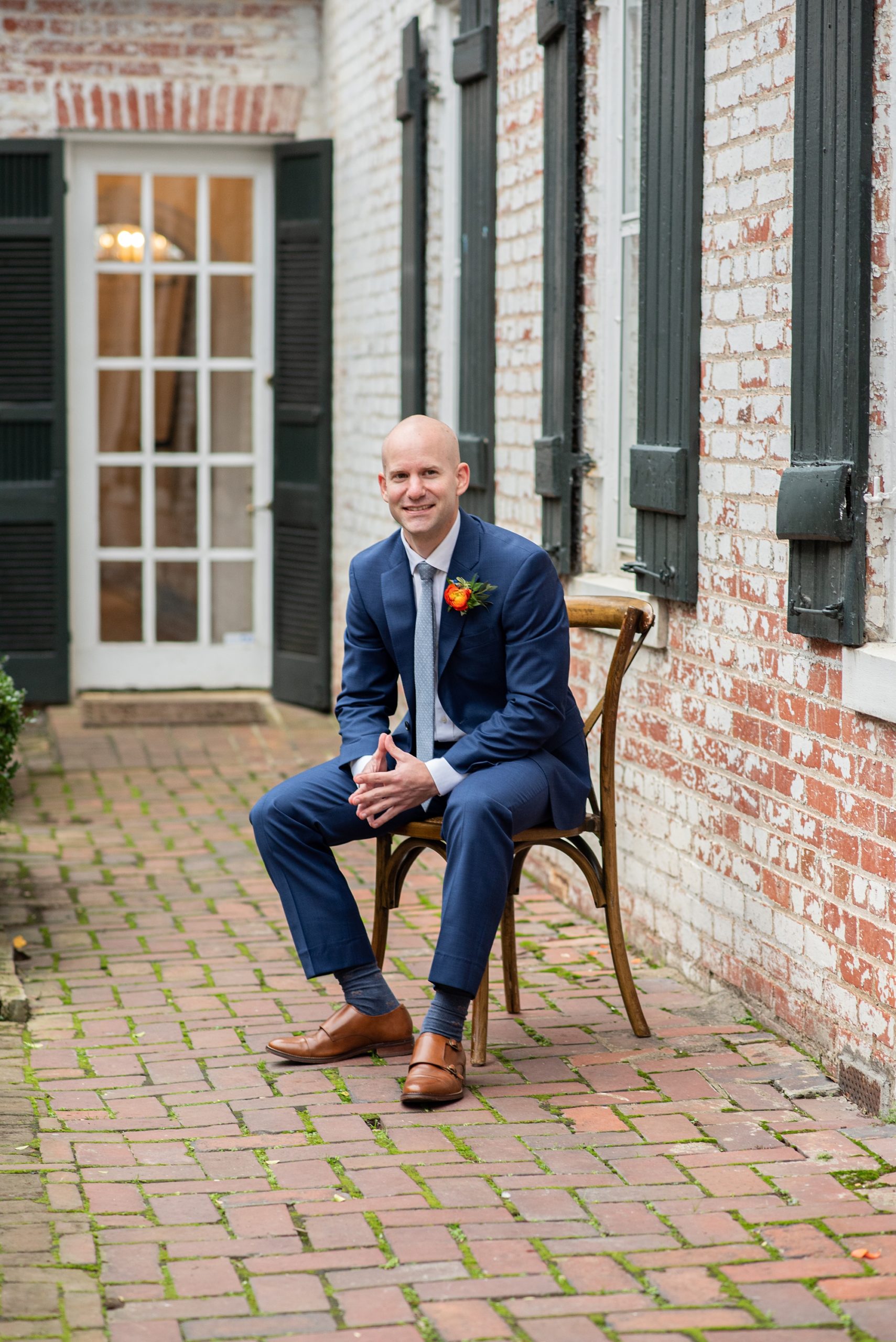 groom sits on wooden chair in Old Town Alexandria 