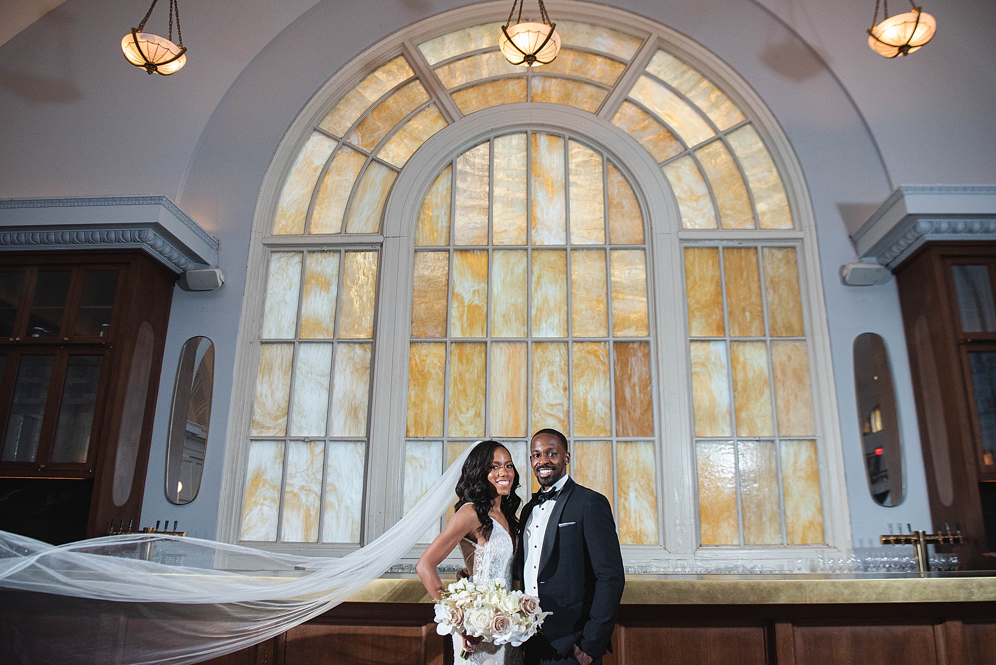 bride and groom pose together by amber window in DC