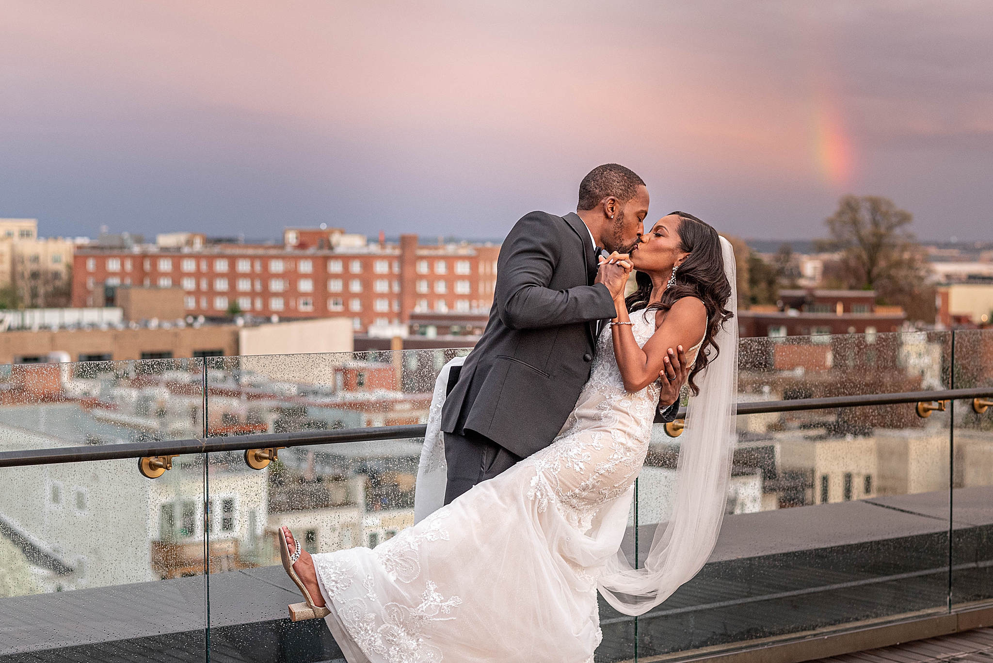 groom dips bride during portraits with rainbow 