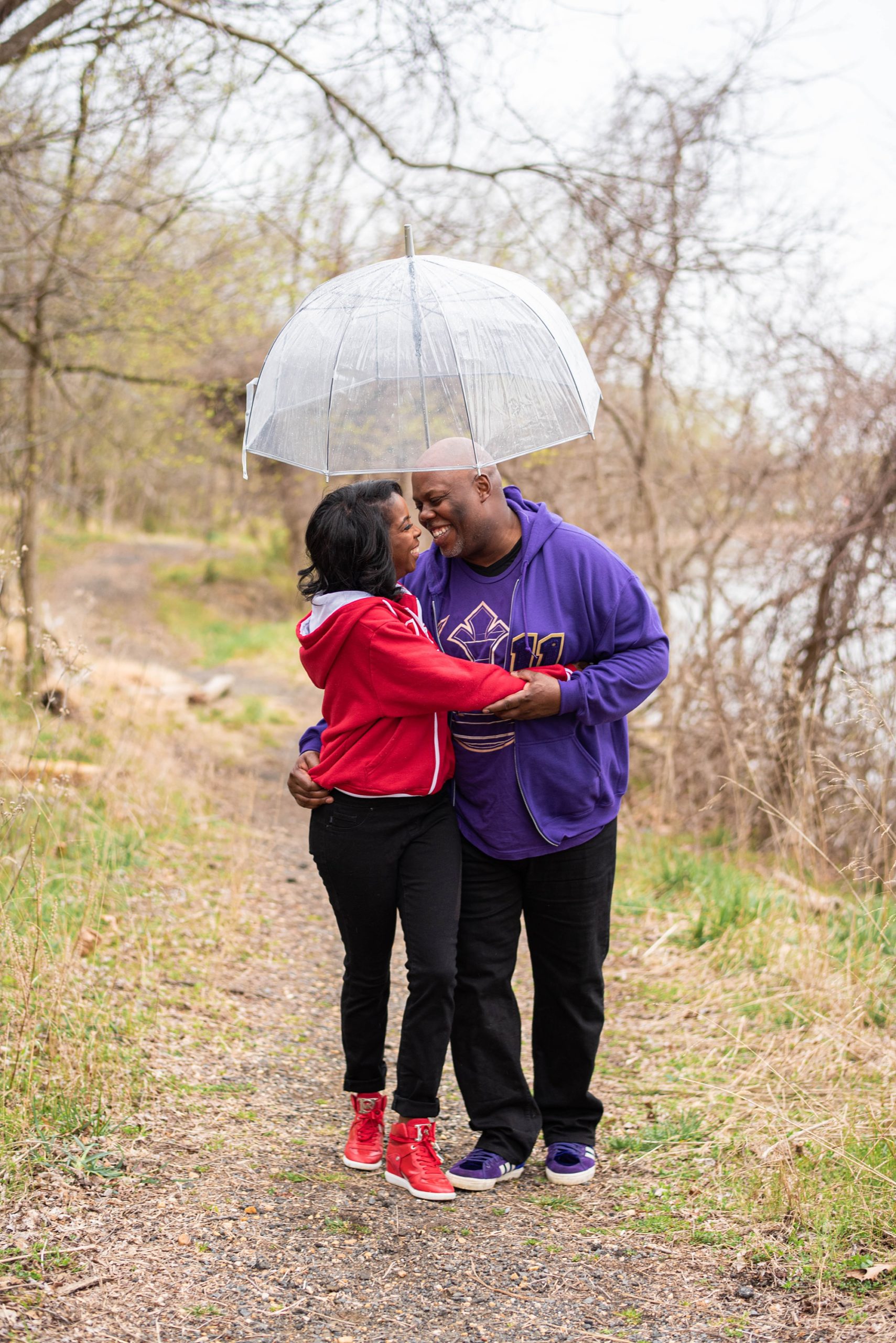 bride and groom hug under clear umbrella in Fort Washington Park