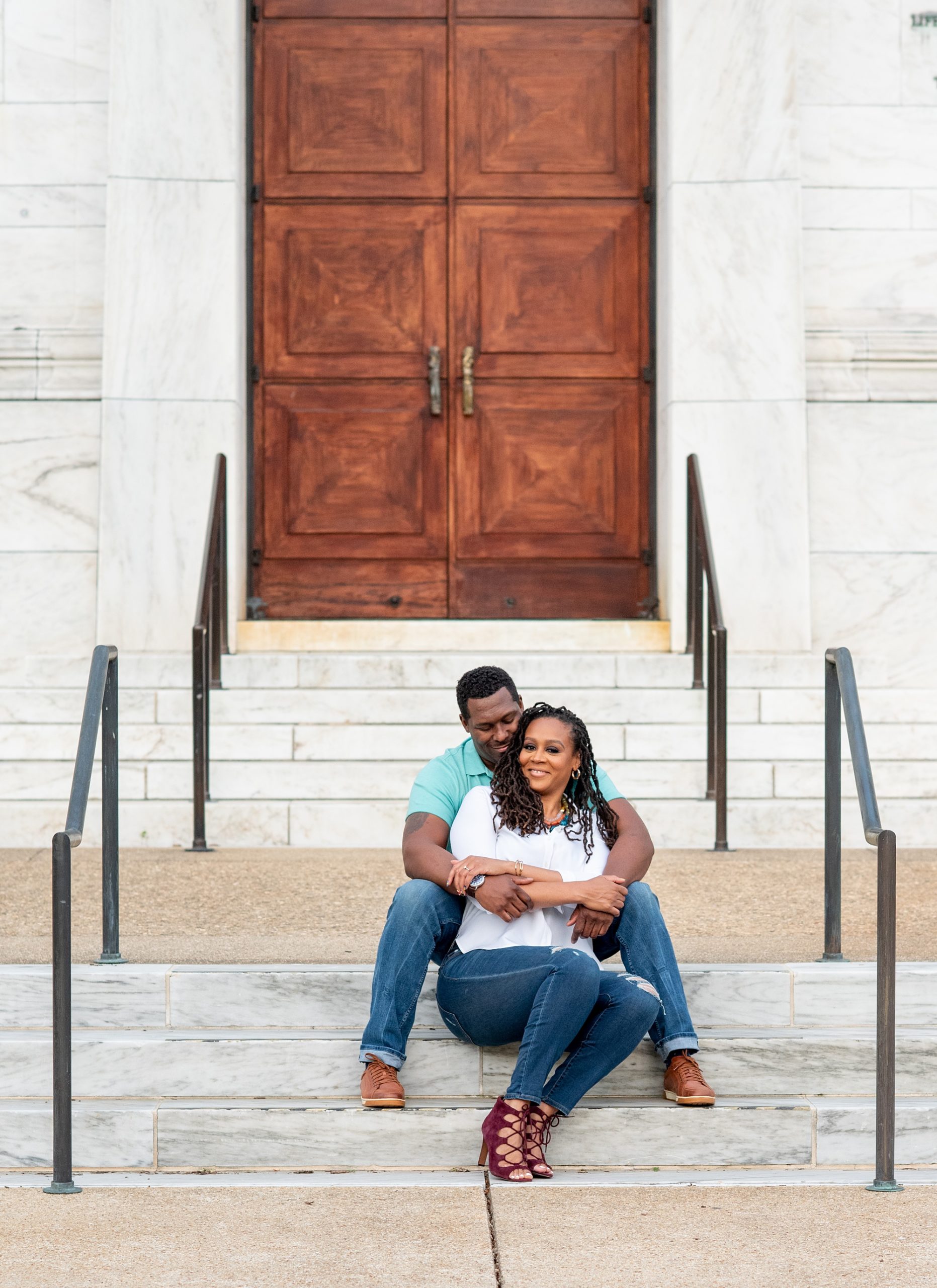 engaged couple sits on steps by wooden door in Washington DC