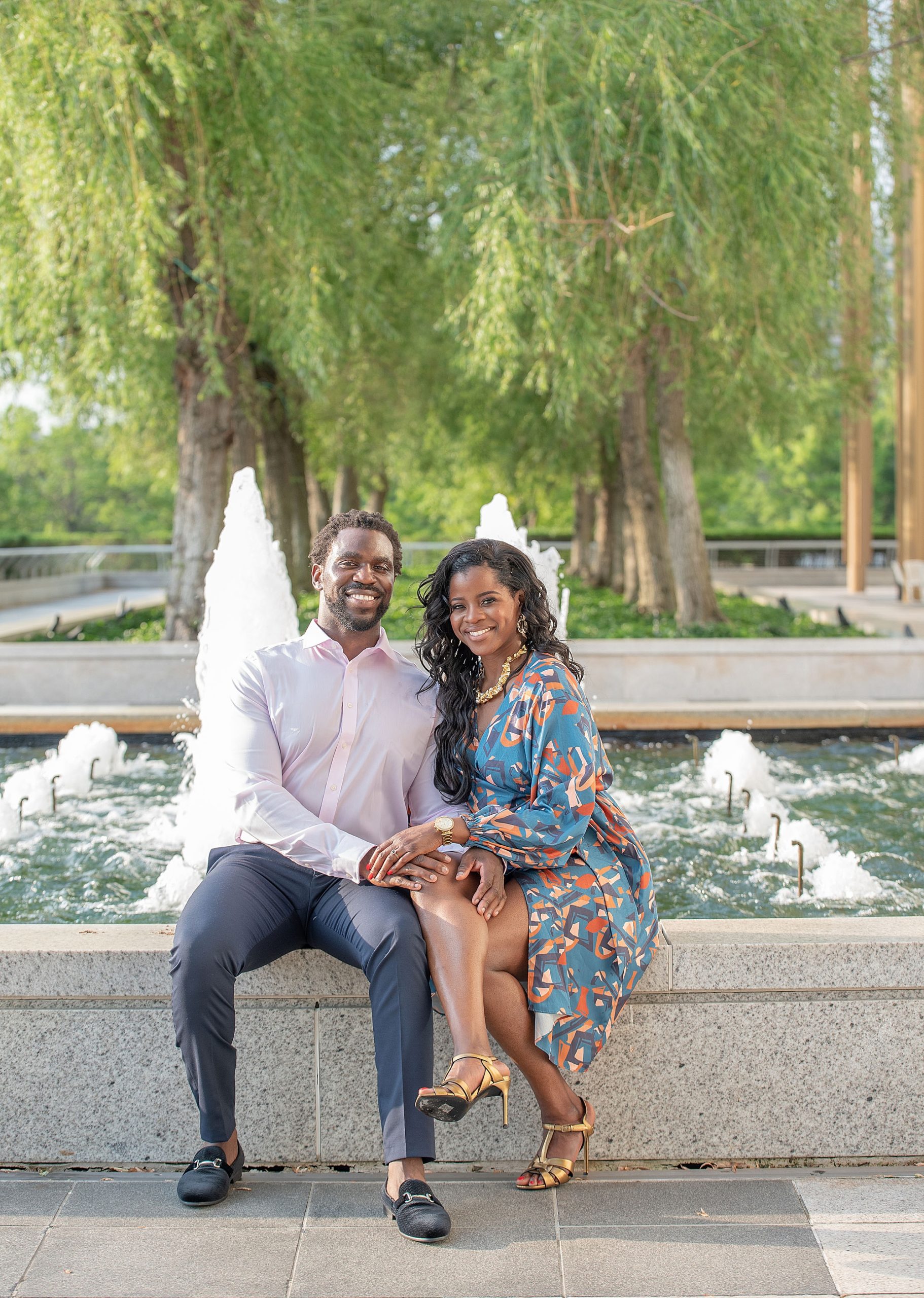 engaged couple sits by fountain at the Kennedy Center