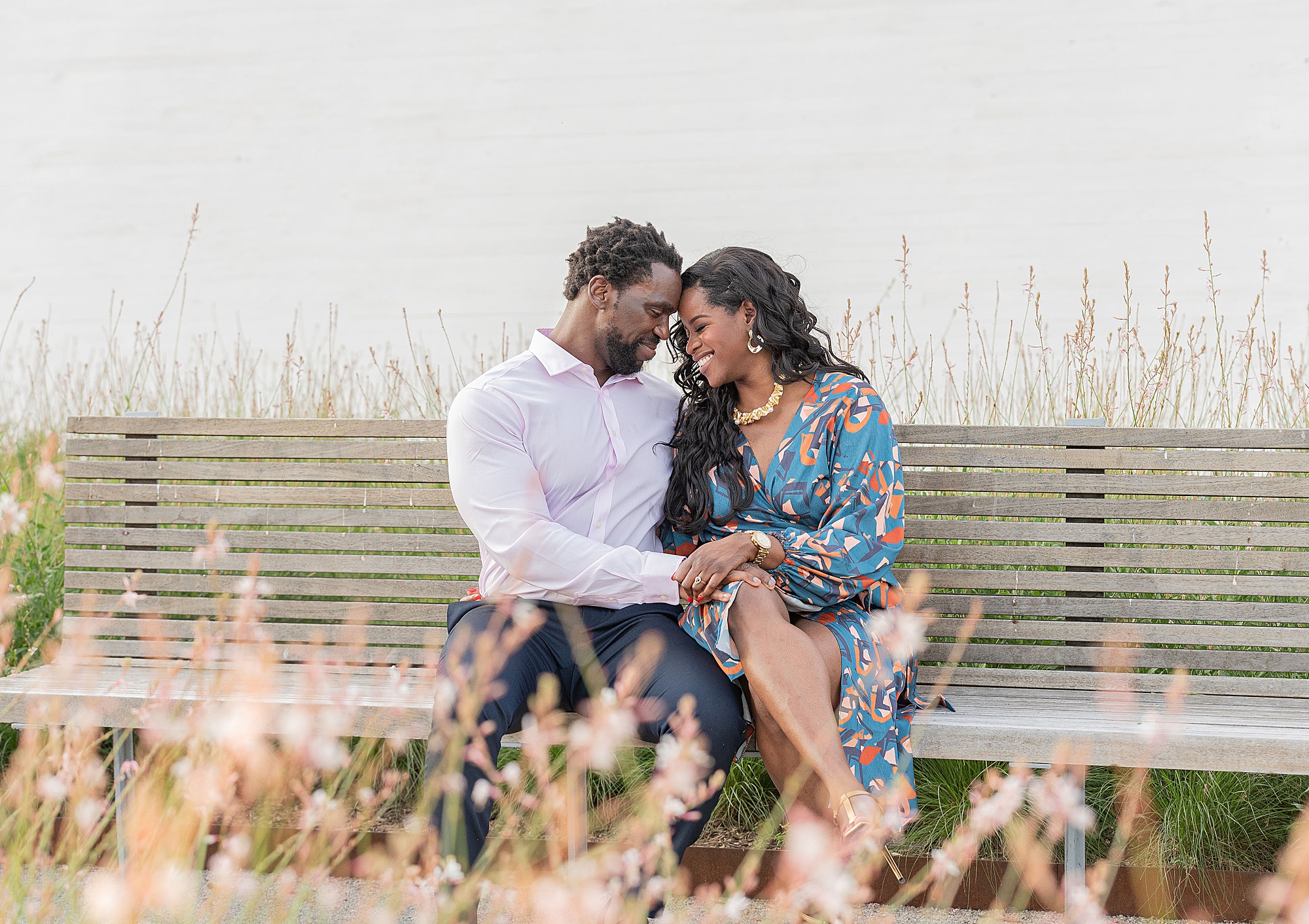 engaged couple sits on wooden bench outside the Kennedy Center