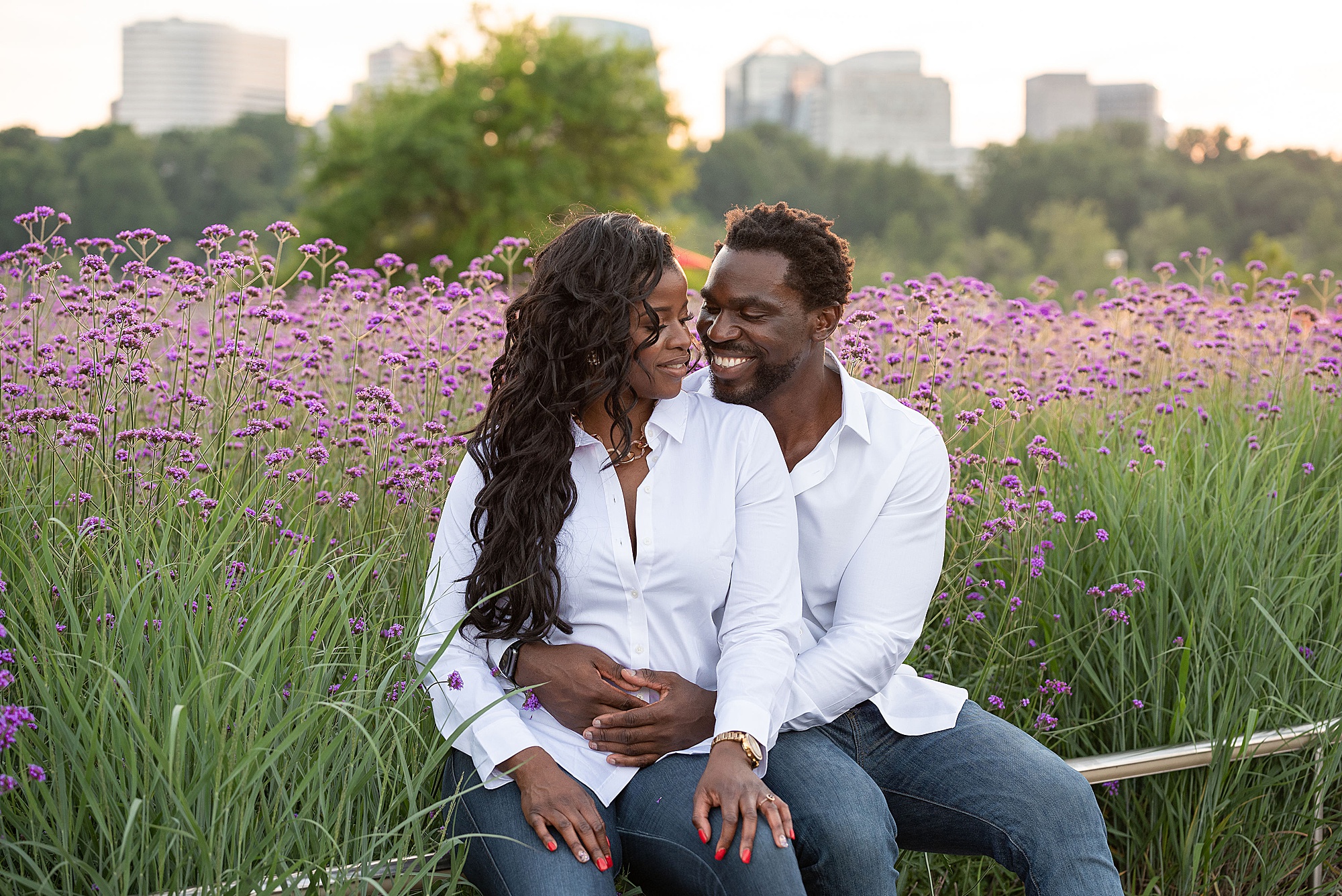 bride and groom sit by pink flowers during Kennedy Center engagement session