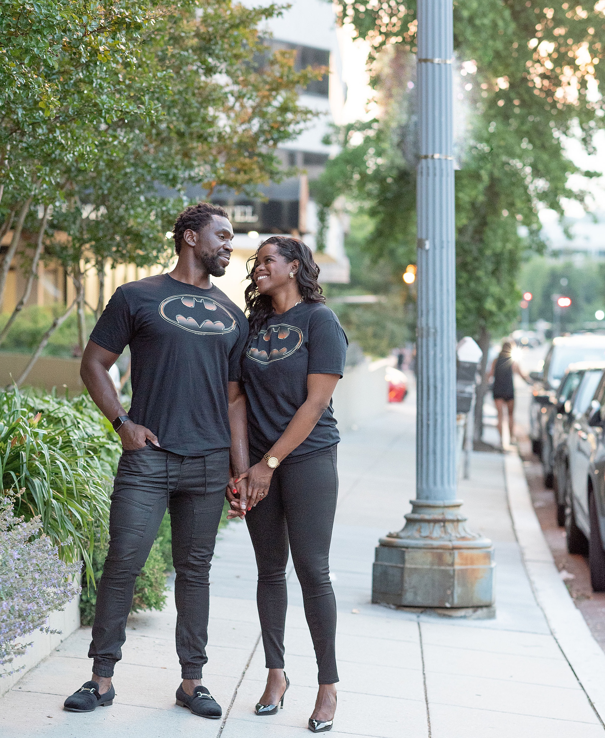engaged couple holds hands on DC street in Batman shirts