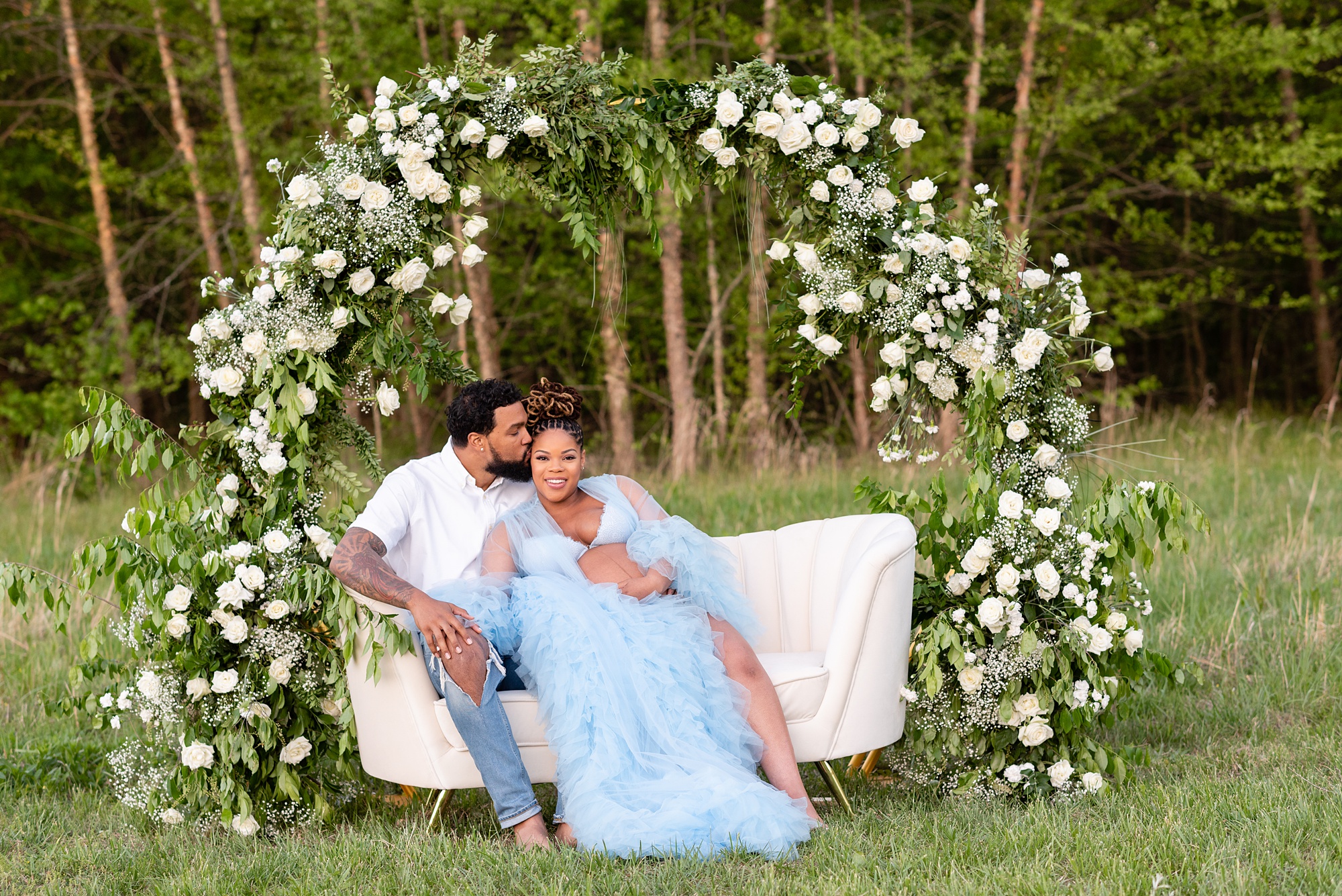 Washington DC maternity photographer photographs mom to be on couch with white floral arbor