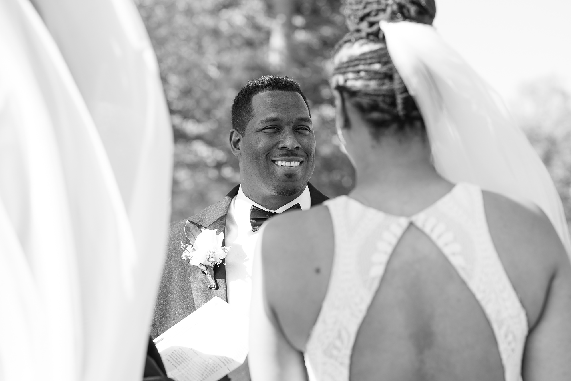 groom smiles at bride during vow exchange 