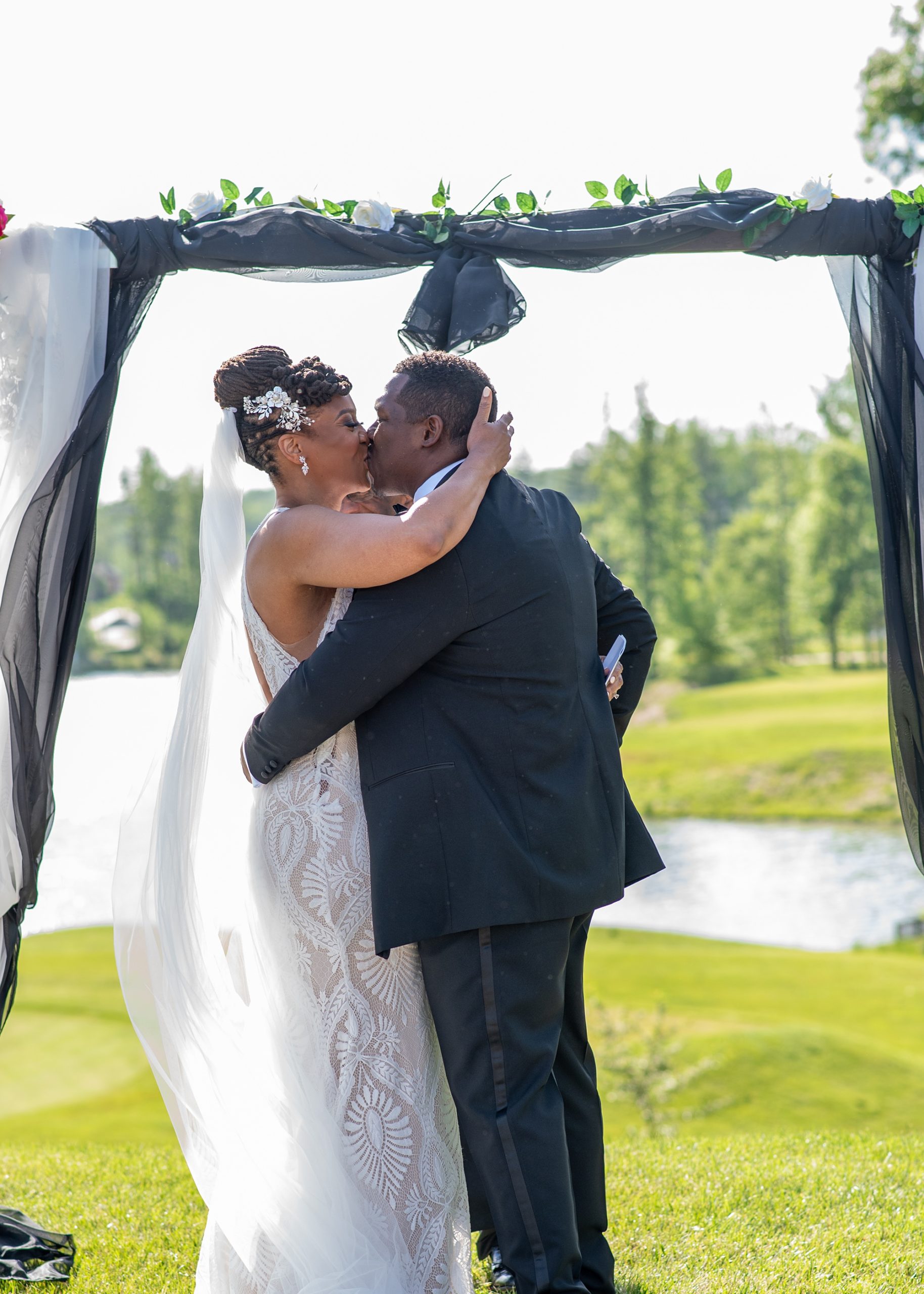 bride and groom kiss under floral arbor in Marlboro MD