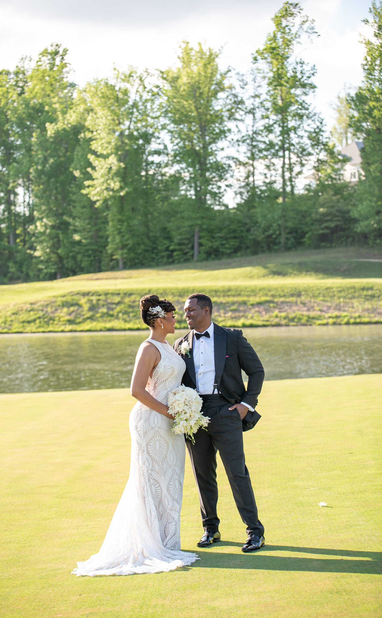 groom looks at bride standing on golf course green