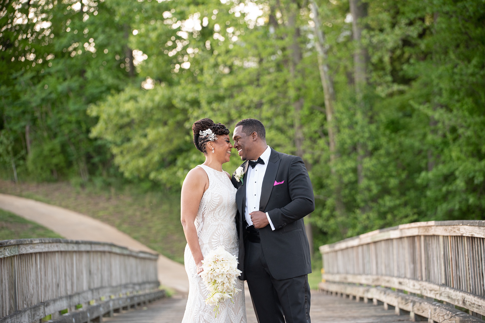 bride and groom stand nose to nose on bridge