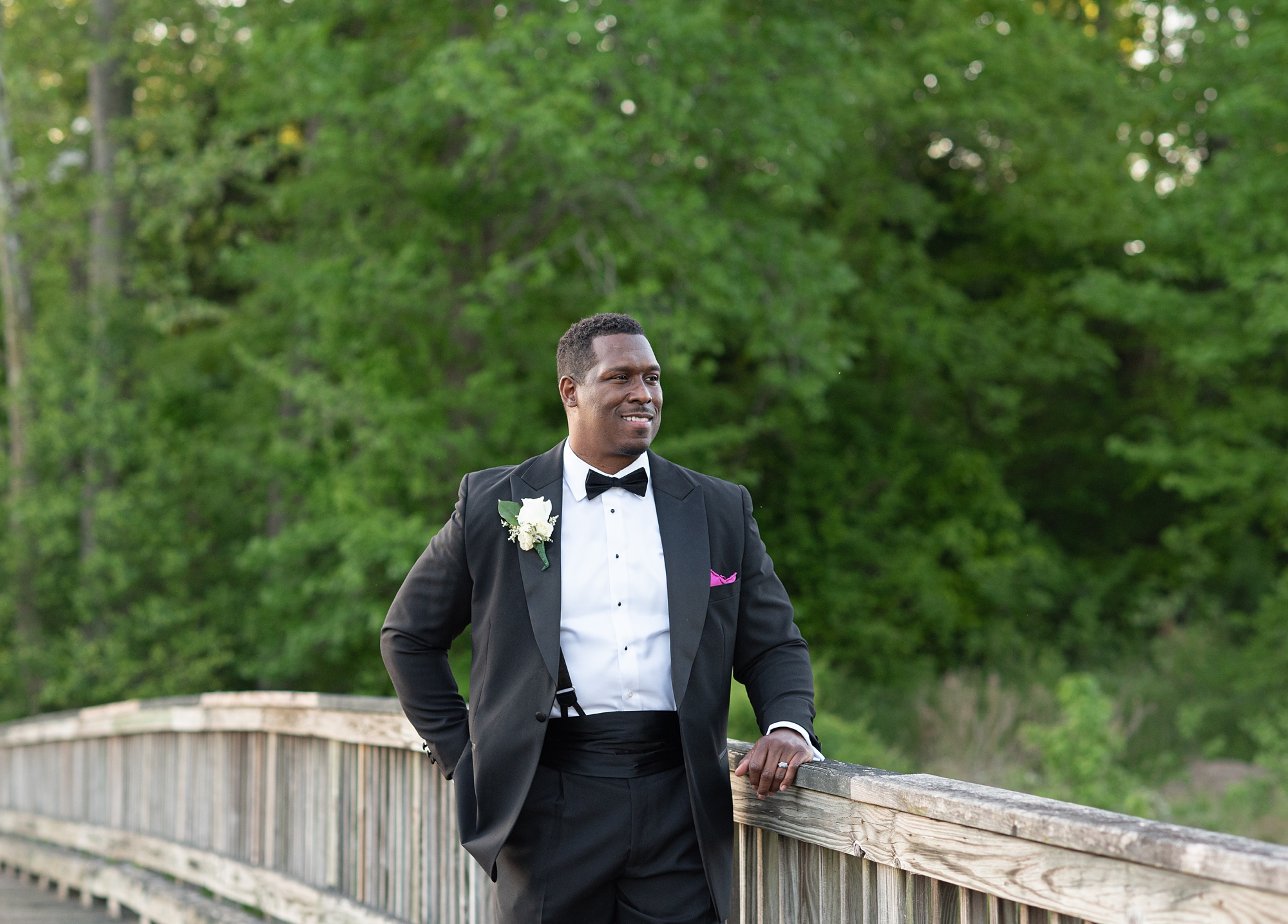 groom stands on wooden bridge in Maryland 