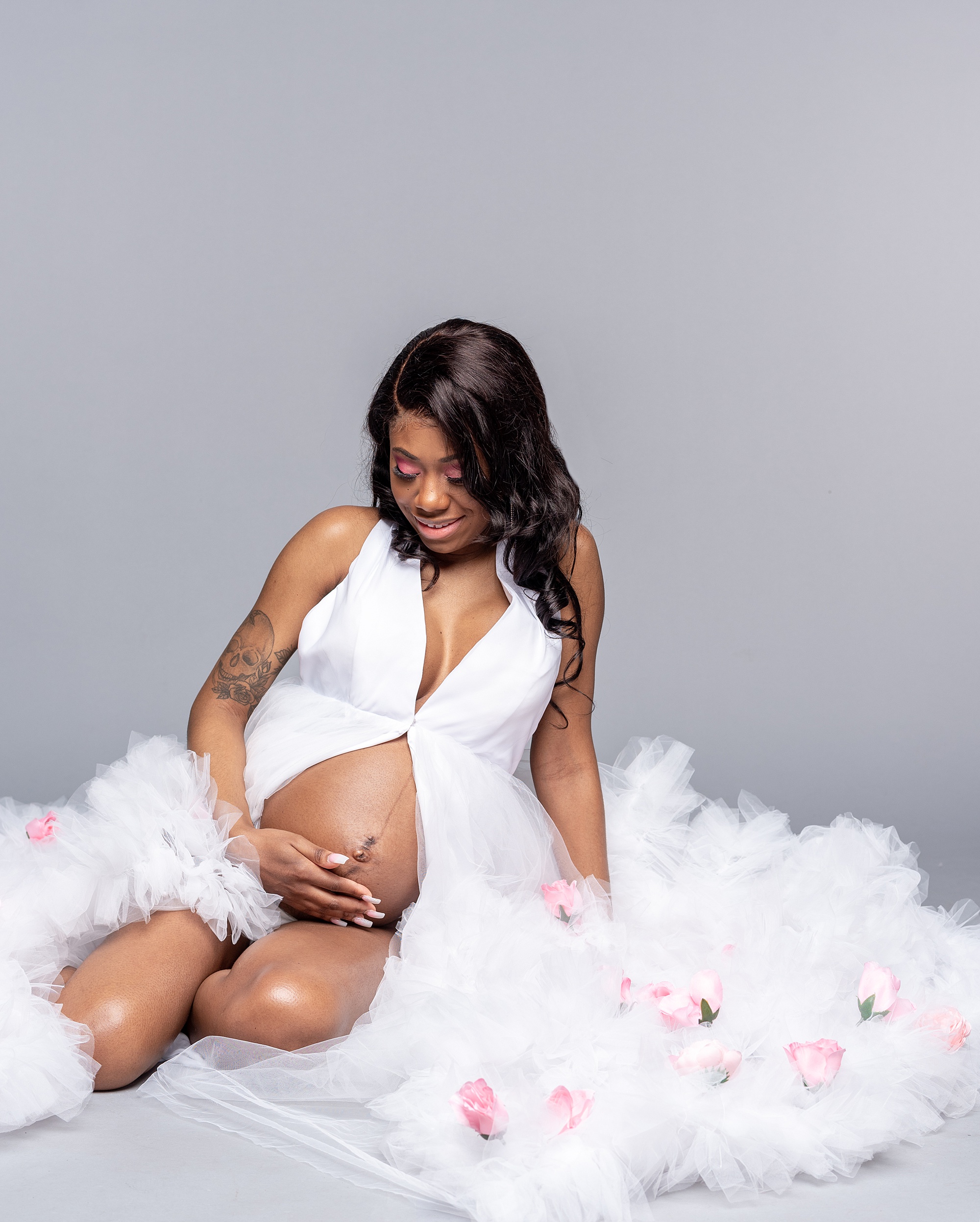 mom sits on floor holding belly during maternity photos