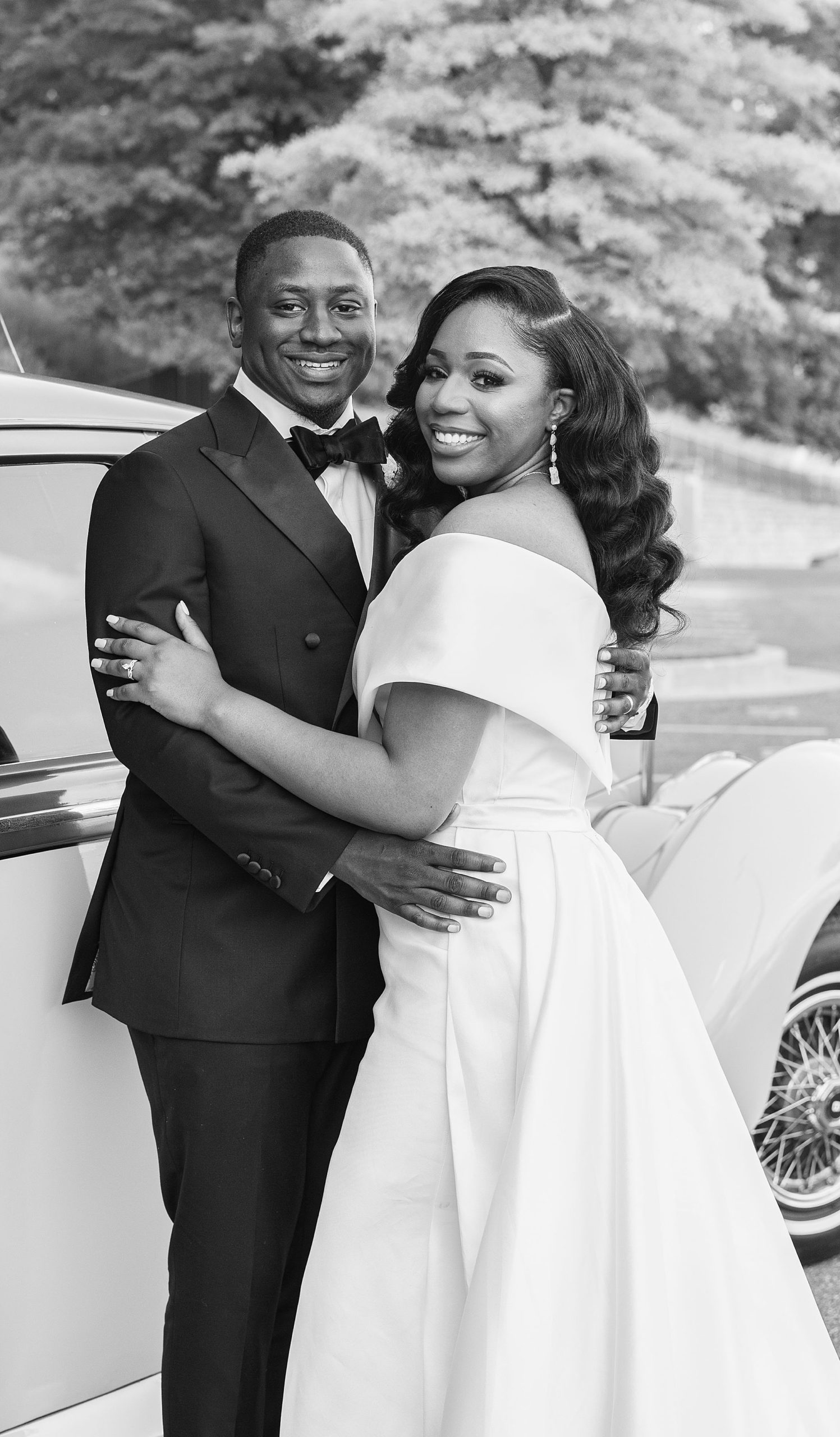 bride and groom pose by classic car