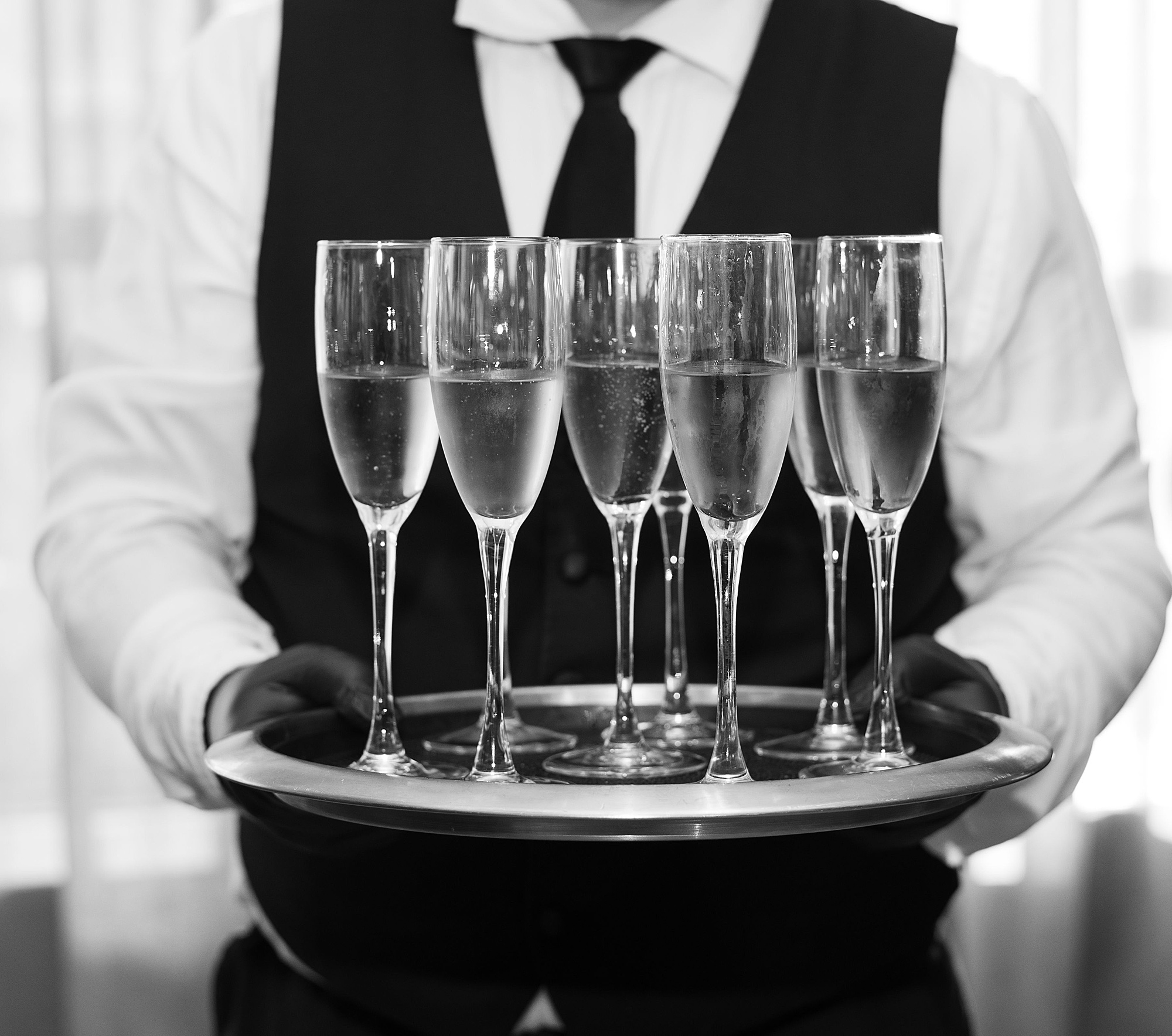server holds tray of champagne