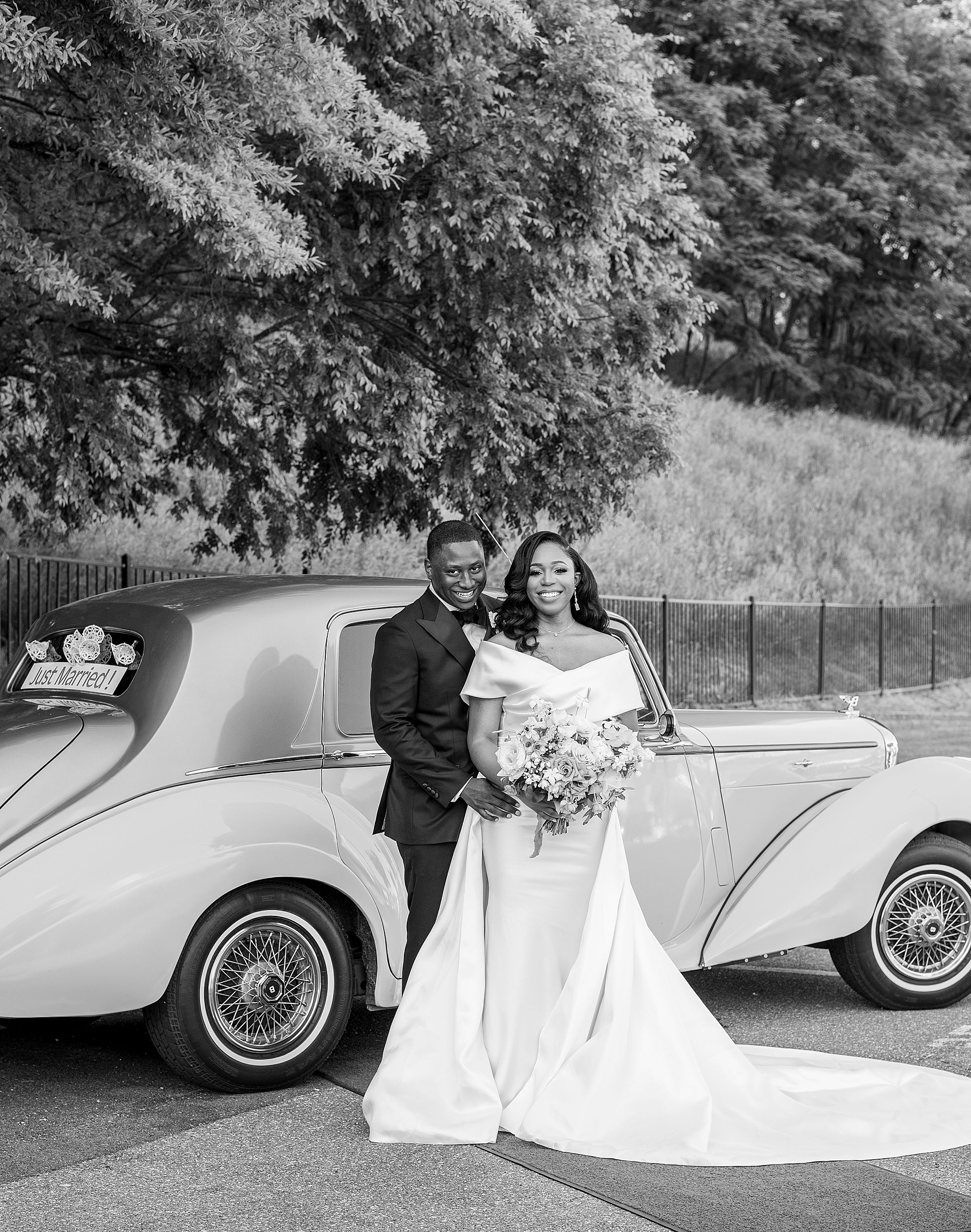 bride and groom pose next to classic car
