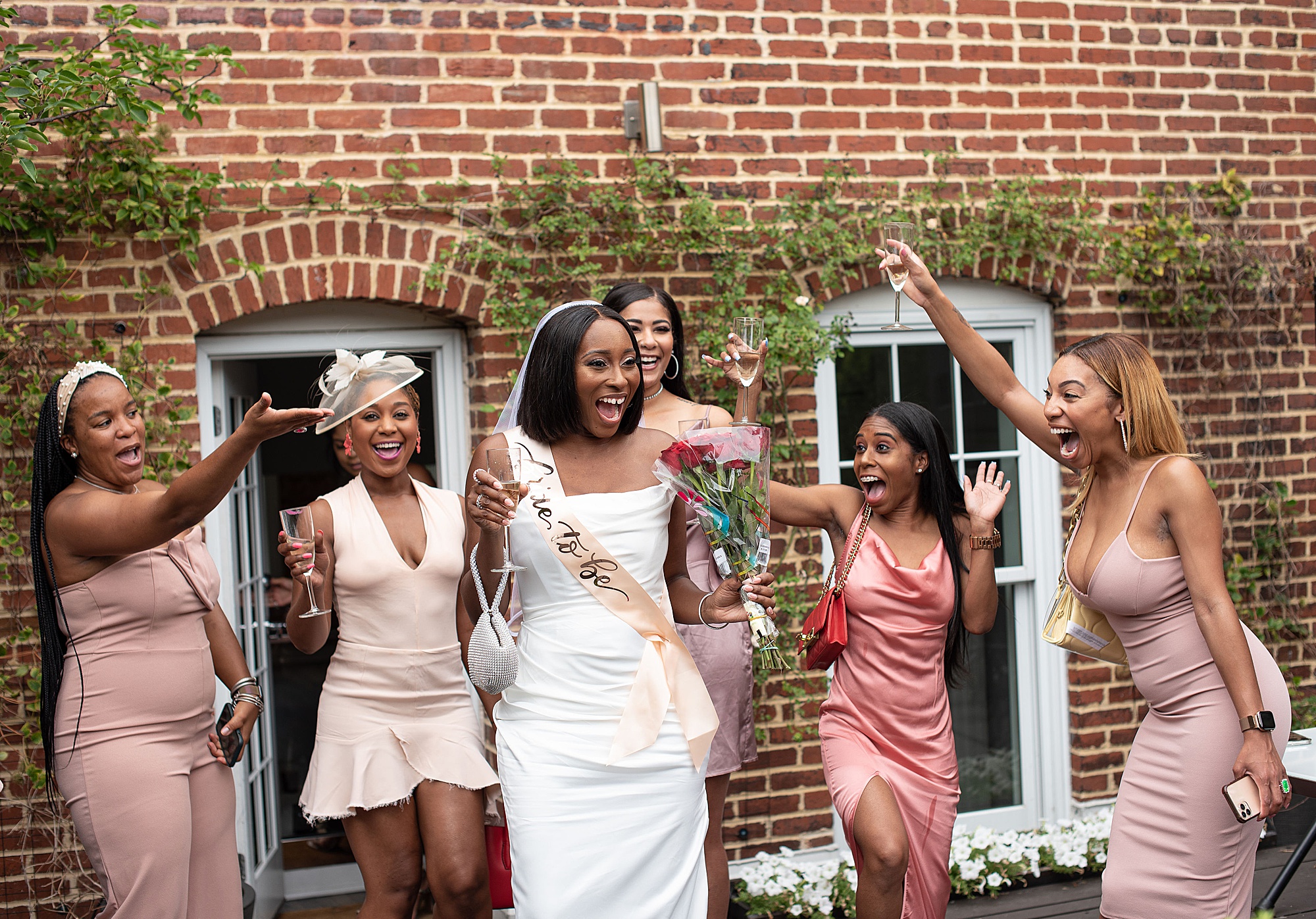 bride laughs with bridesmaids outside Fathom Gallery