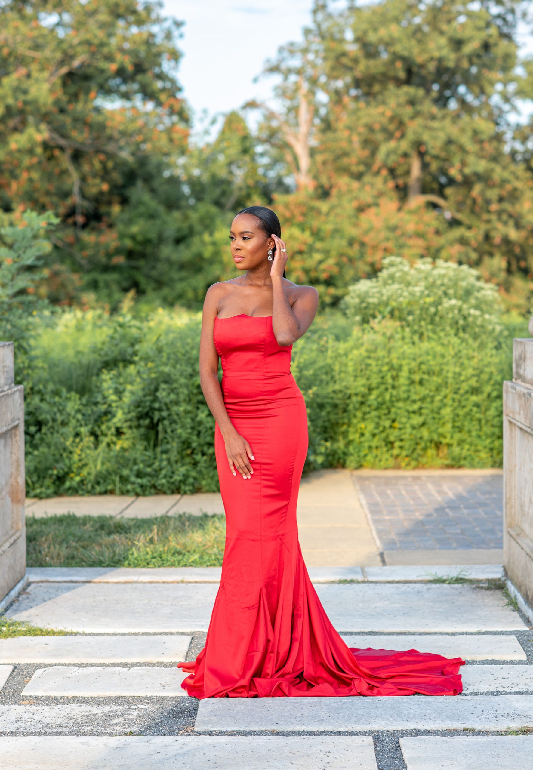 bride in red dress pushes hair behind her ear during DC engagement photos 