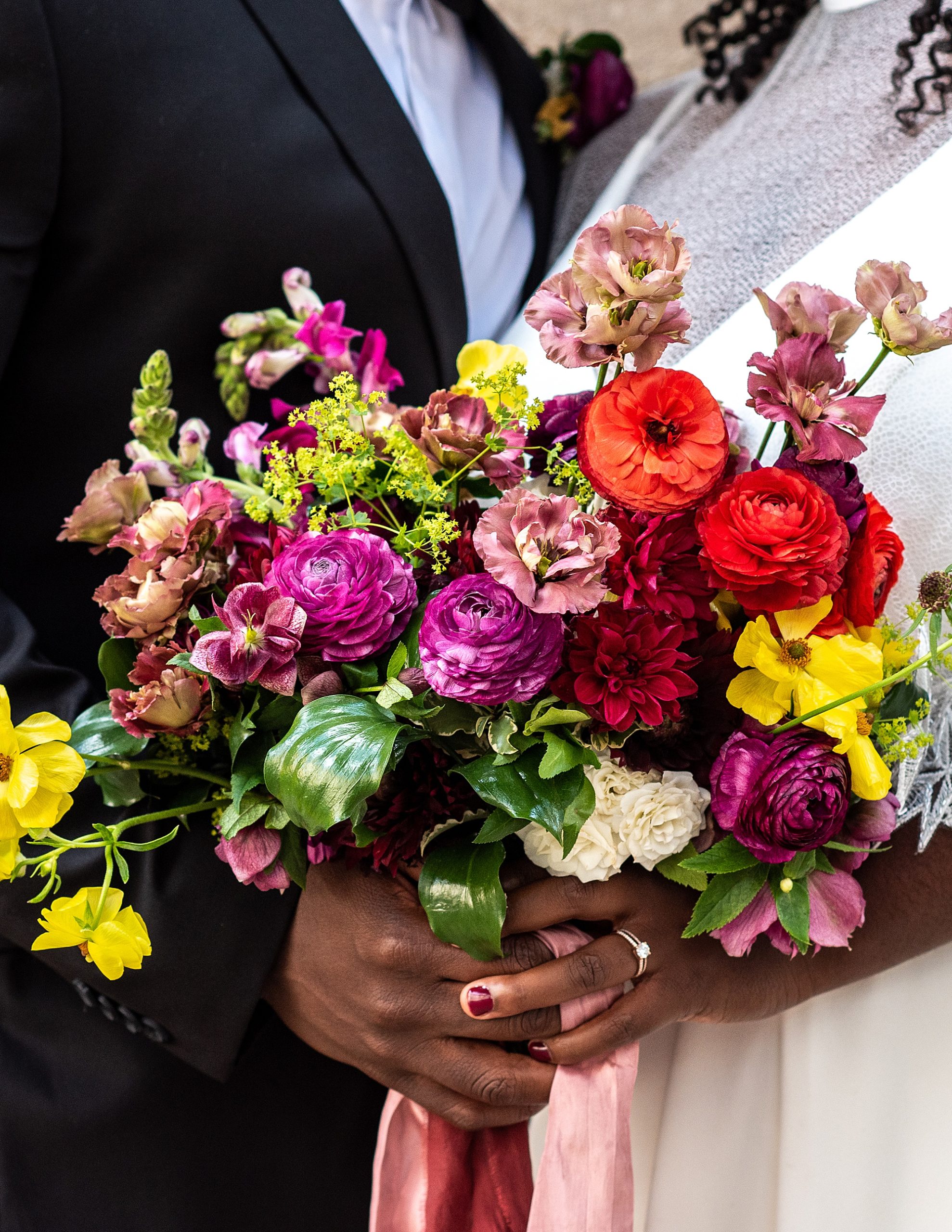 bride and groom hold onto bride's bright bouquet 