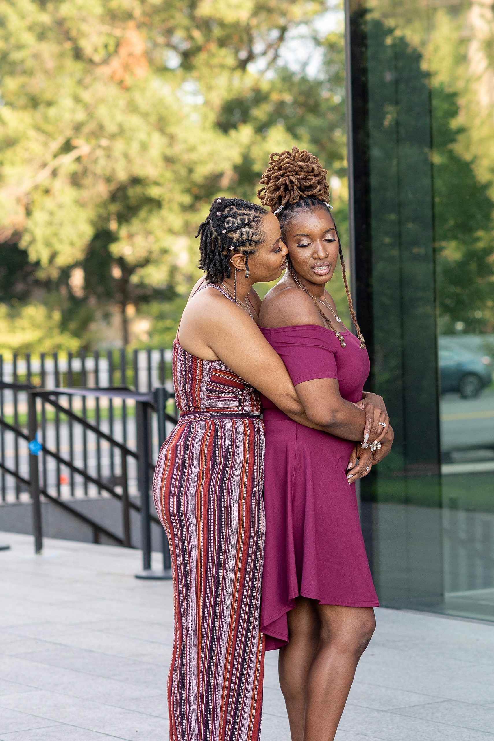 woman hugs wife from behind by National Museum of African American History and Culture