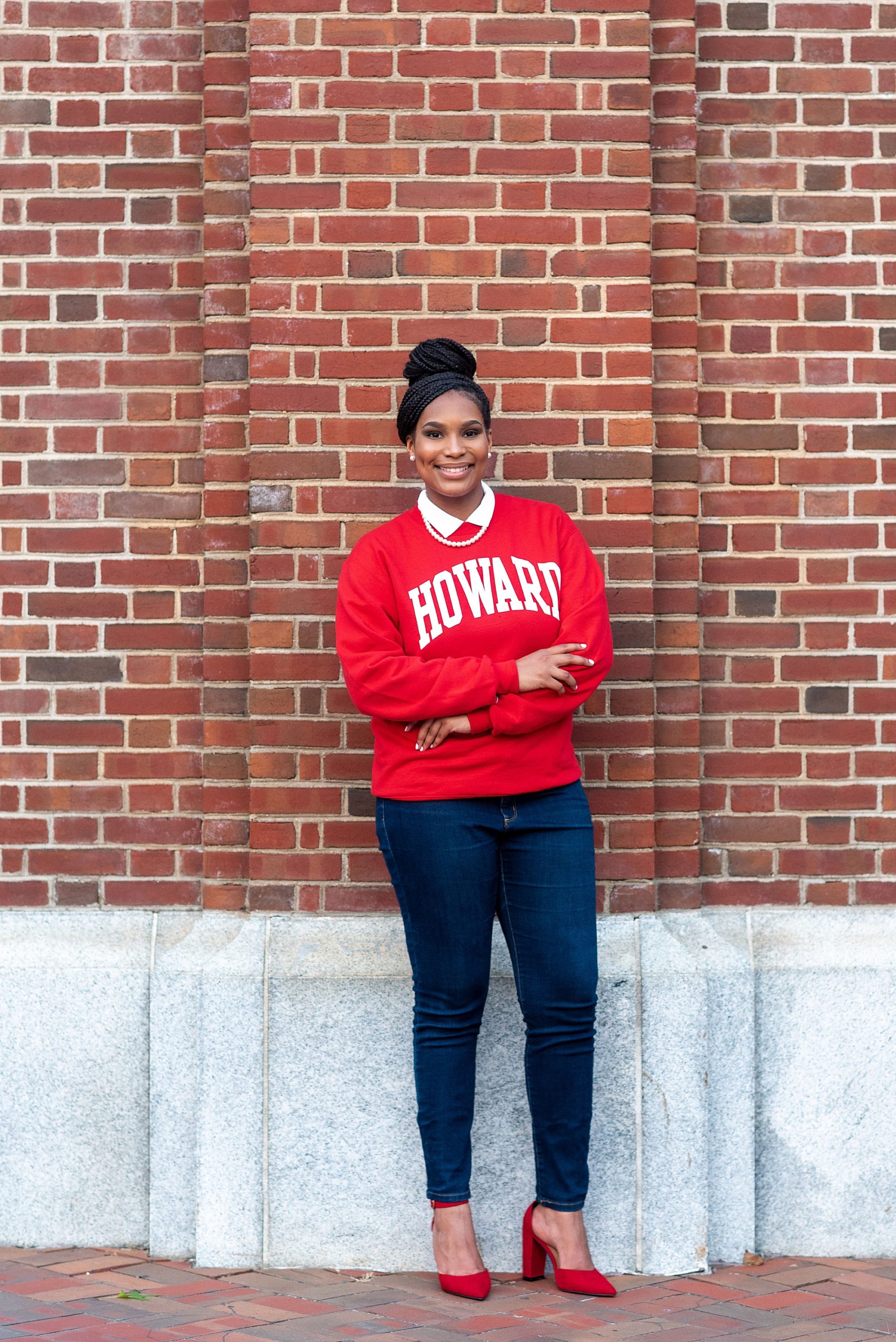 student leans against brick wall at Howard University