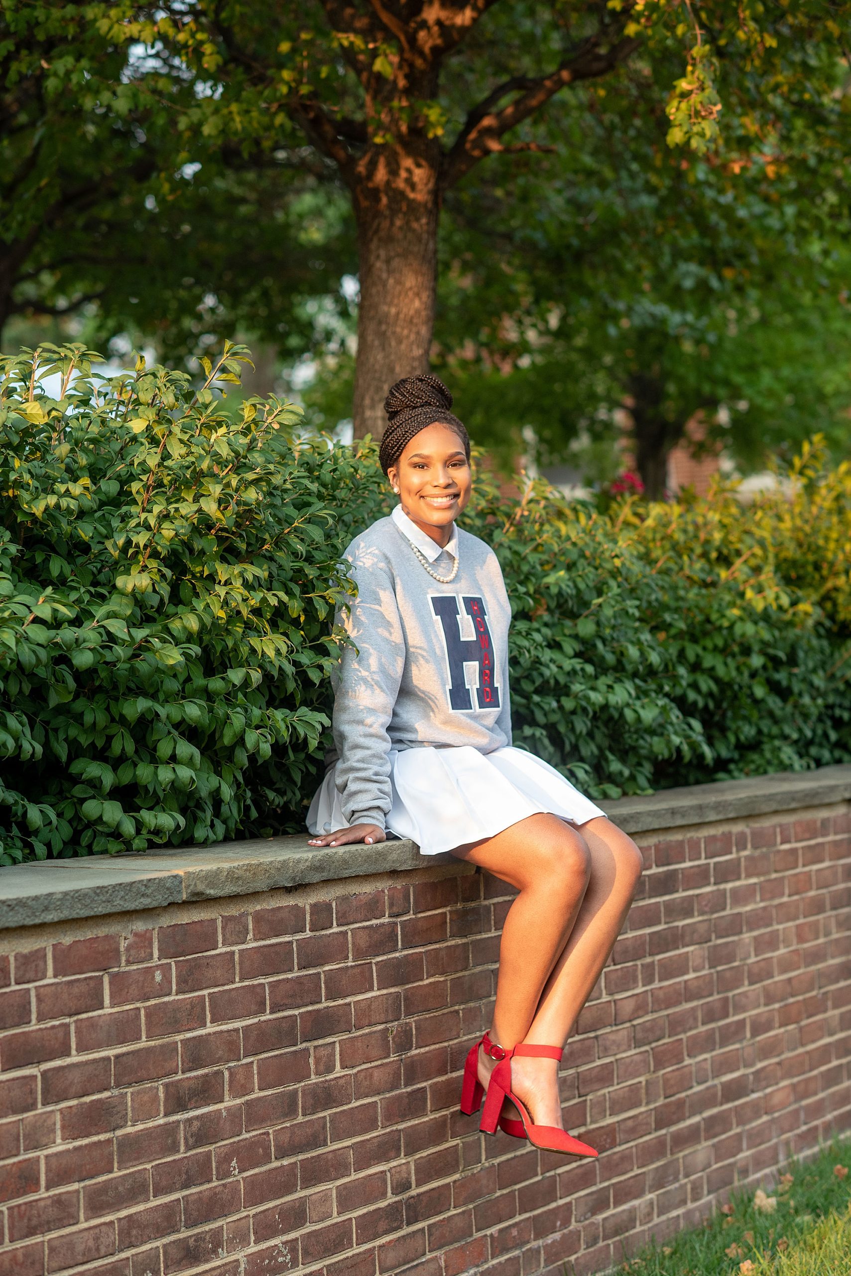 student sits on brick wall during Howard University freshman portraits 