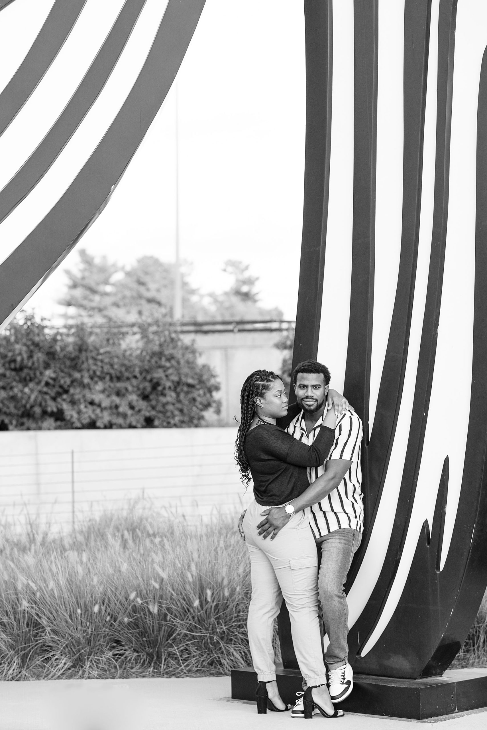 engaged couple hugs by black and white sculpture during Kennedy Center engagement portraits