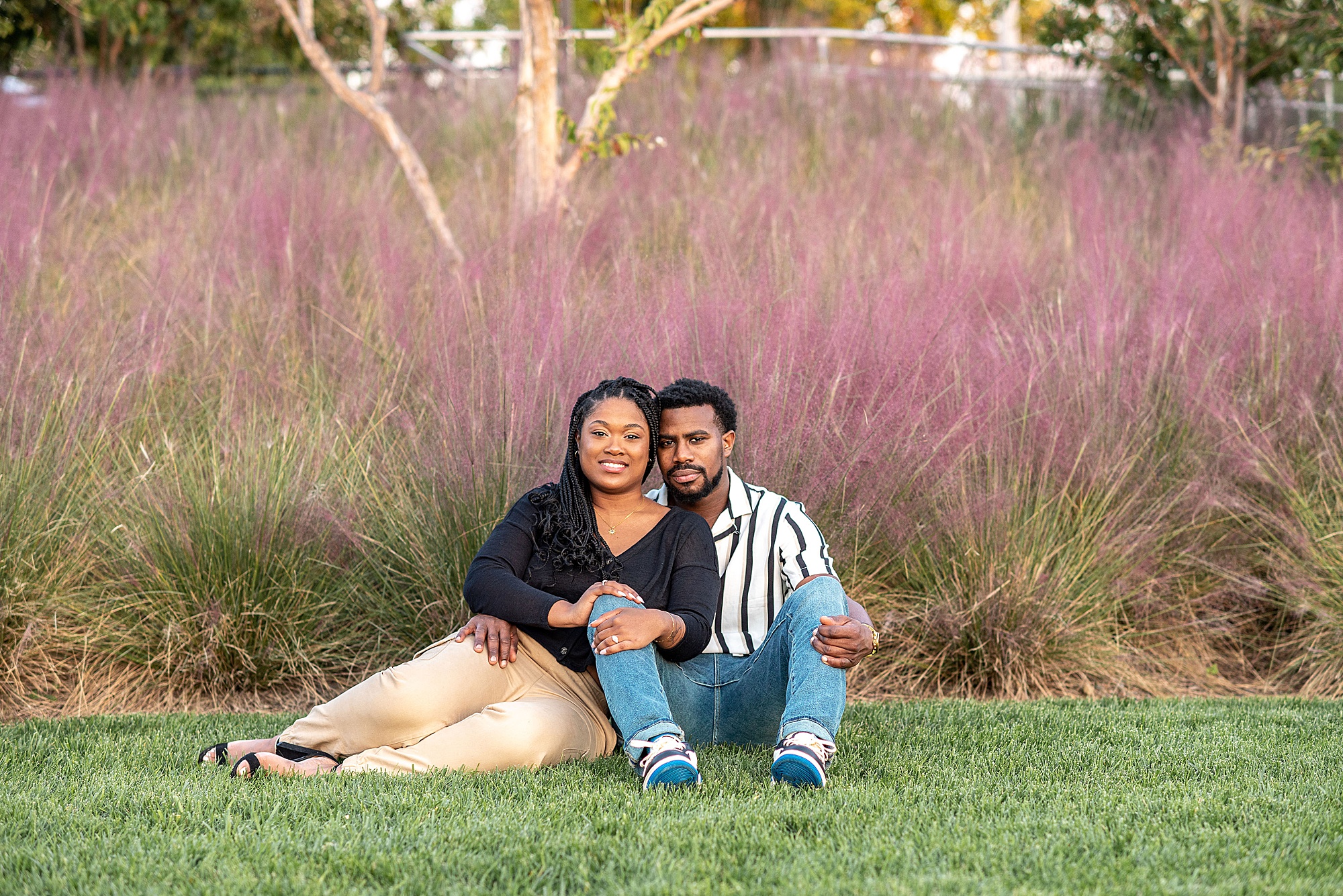 couple sits by pink bush during DC engagement session