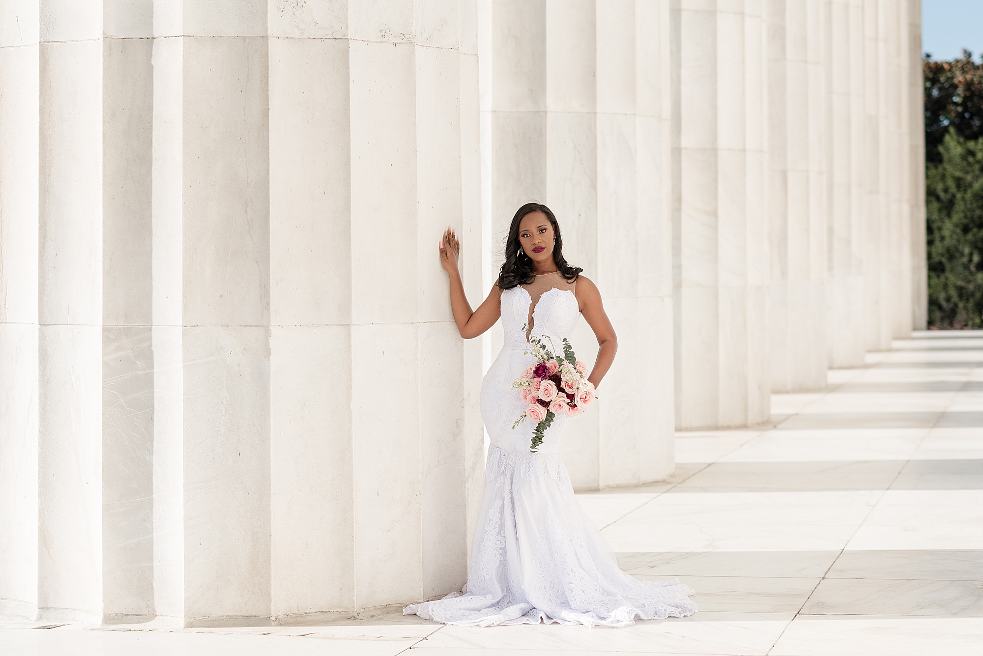 bride leans against column of Lincoln Memorial with one arm