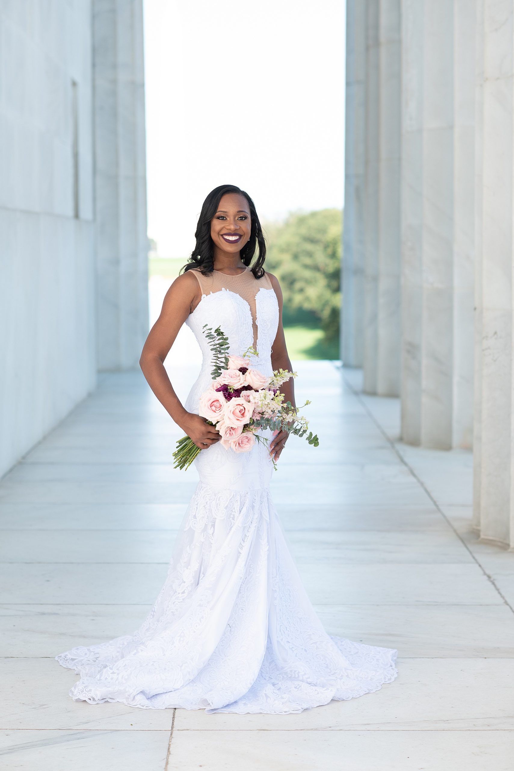 bride poses between columns at the Lincoln Memorial with flowers on her hip