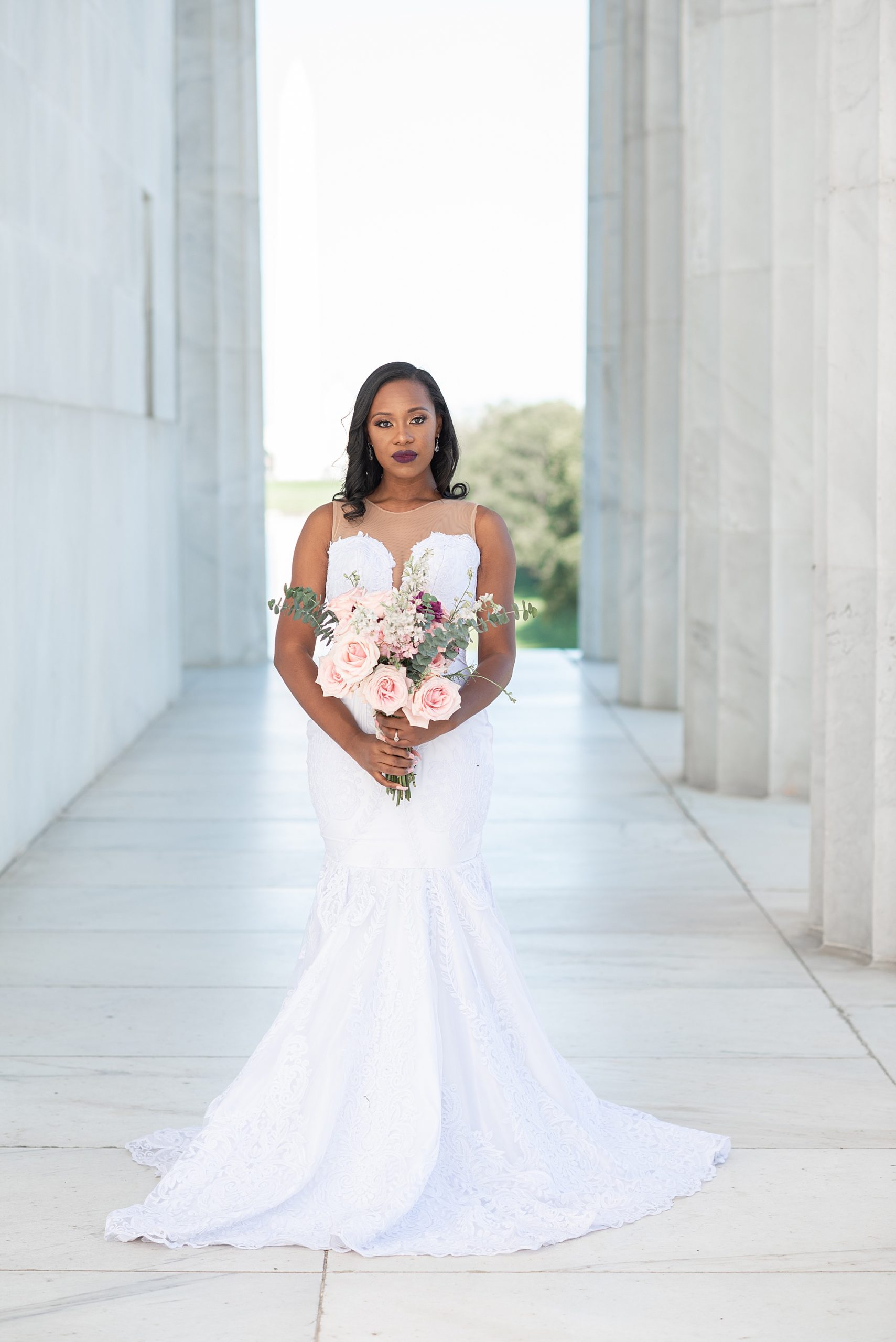 woman holds bouquet of pink flowers during Lincoln Memorial bridal portraits