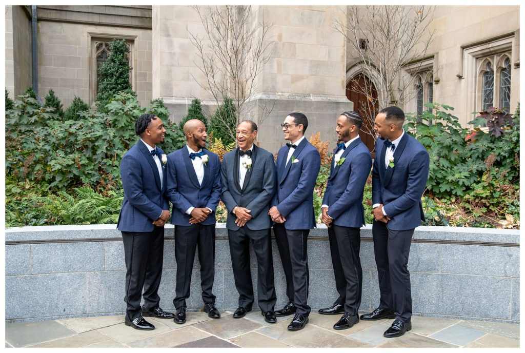 groom and groomsmen posing for group photos in front of church