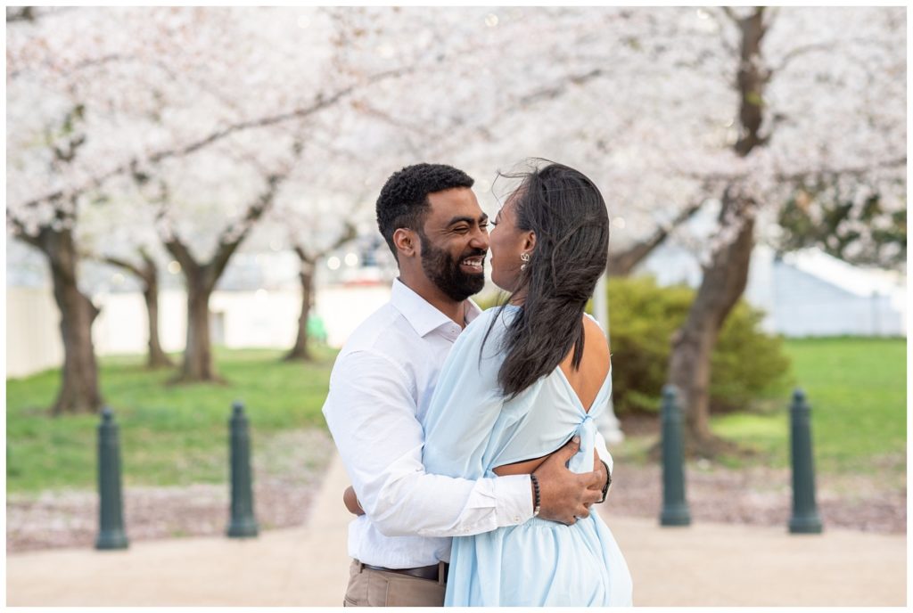 couple hugging and smiling outside under cherry trees