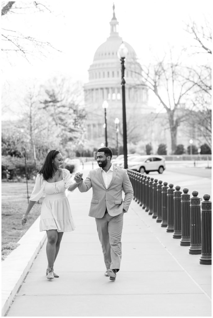 couple walking and holding hands in front of the Capitol building in D.C.