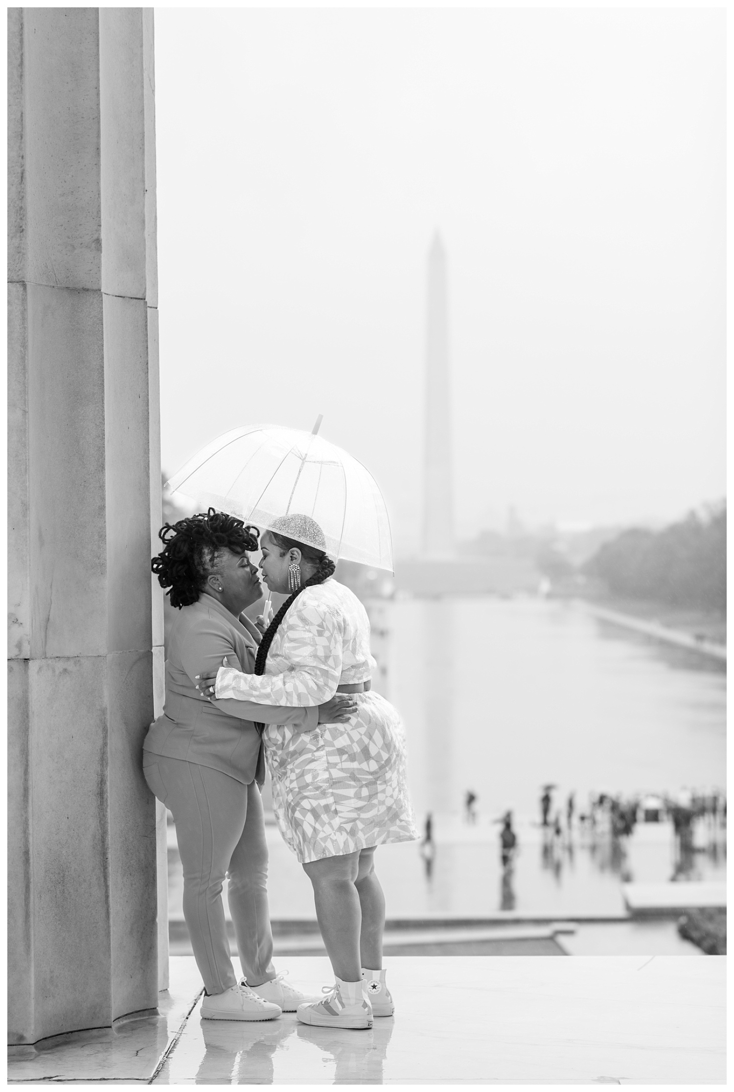 female couple standing under a clear umbrella at engagement session