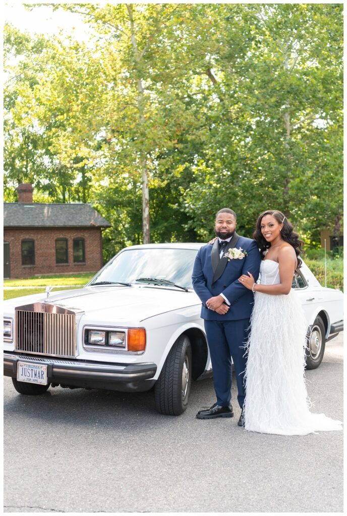 bride and groom pose in front of white classic car at reception