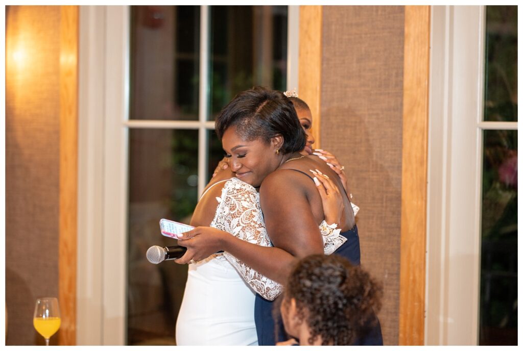 bride and sister hugging after speech at wedding repcetion